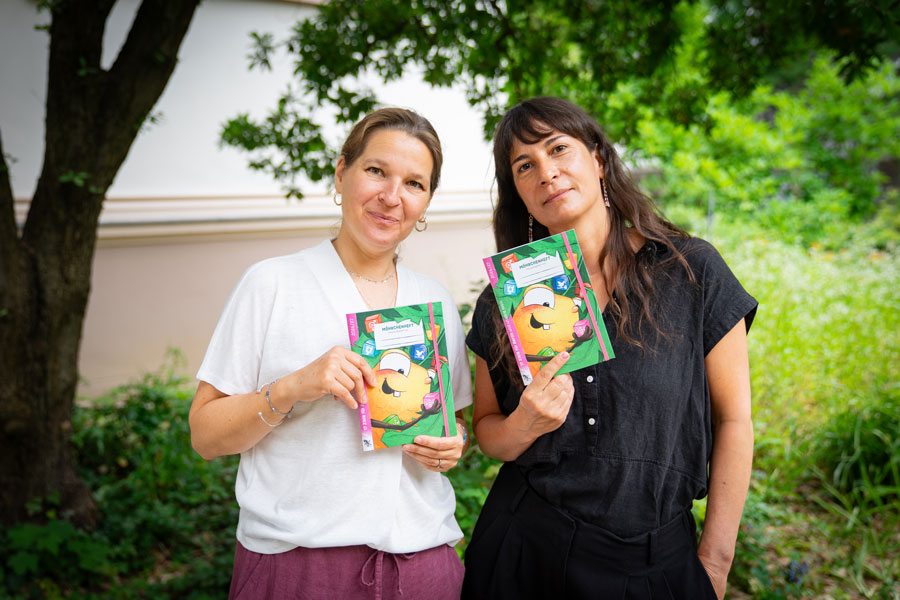 Auf dem Bild stehen Juliane Brix und Lidia Perico mit den neuen Heften in der Hand nebeneinander im Grünen